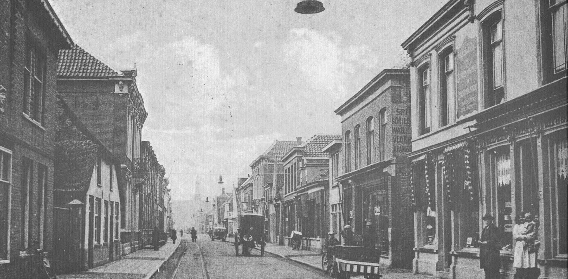 Overzicht van de Grotestraat in Waalwijk in de vorige eeuw waar reclame en beeld nog aan de gevel van een bakkerij hing